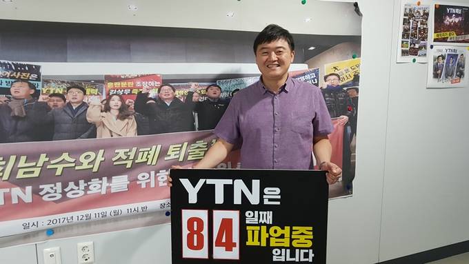 2년2개월여 만에 현업에 복귀하는 박진수 전국언론노조 YTN지부장이 기자협회보와 인터뷰에서 'YTN은 84일째 파업 중"이라는 문구가 쓰인 팻말을 들고 활짝 웃고 있다.  