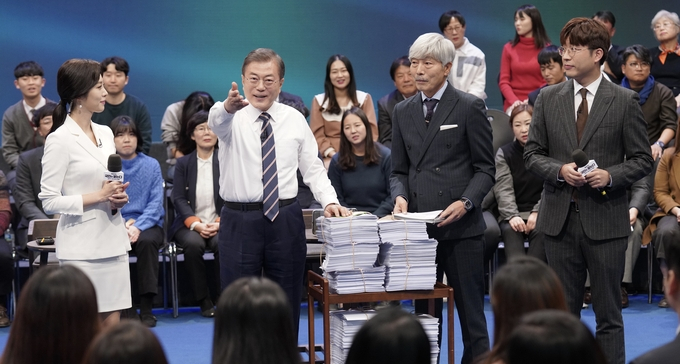문재인 대통령이 19일 오후 서울 상암 MBC미디어센터에서 열린 ‘국민이 묻는다, 2019 국민과의 대화’에 참석해 국민패널과 온라인 참여자 질문지를 받고 있다. /뉴시스 